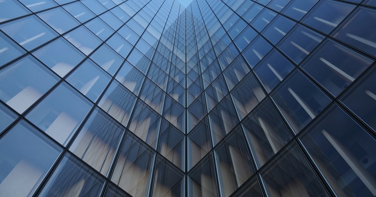 Looking straight up a glass skyscraper whose window grid narrows toward the sky