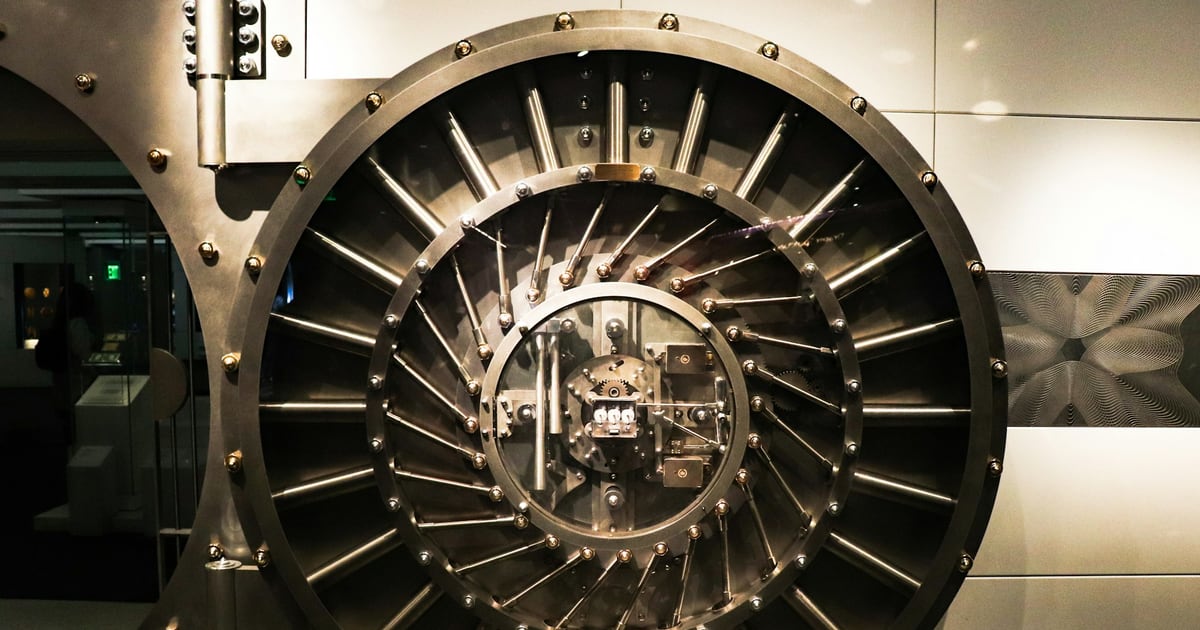 A round steel bank vault door, its locking bolts arranged in a ring around the center hub